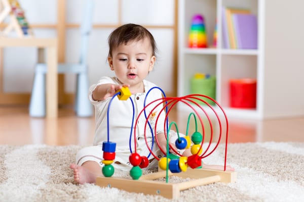 Infant playing with age-appropriate bead toy